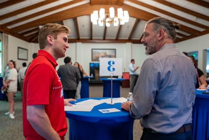 two guys talking at blue table